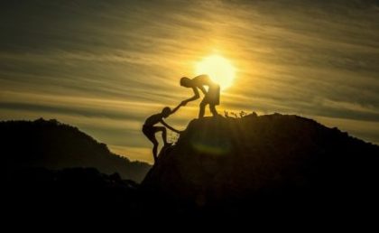 Una persona aiuta un'altra a scalare una montagna - immagine simbolica.